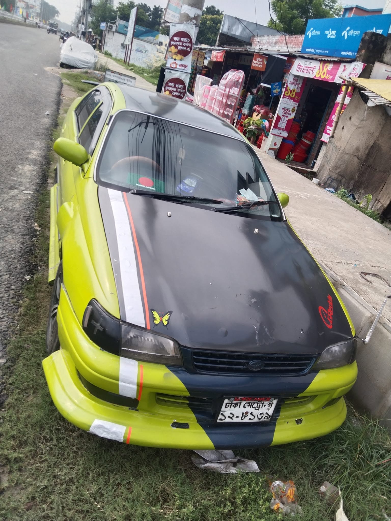 Front view of Famous Driving Center car with Dhaka Metro license plate in Rajshahi.